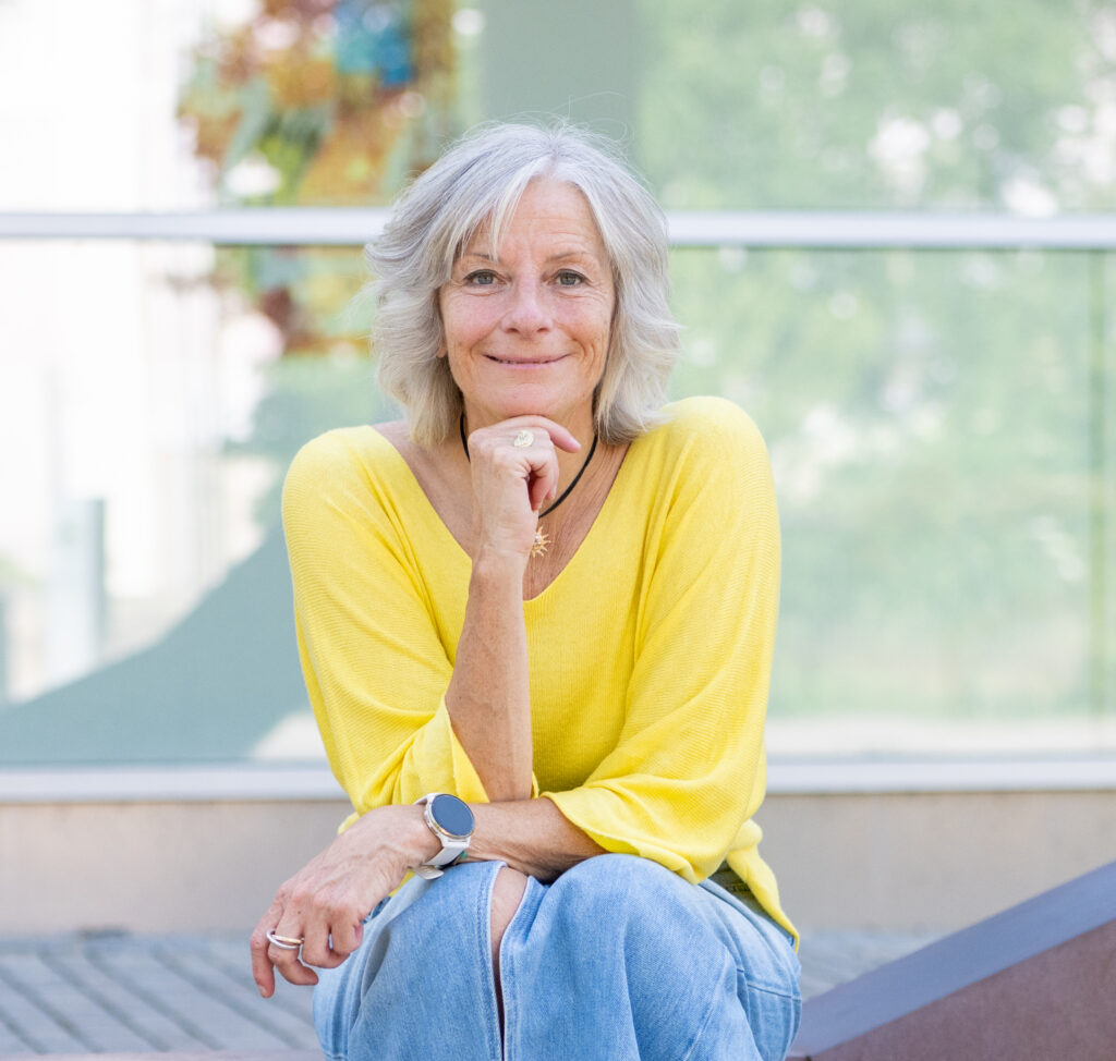 Sandra Jost, gelbes shirt, Kinn mit Hand aufgestützt, gelbes shirt